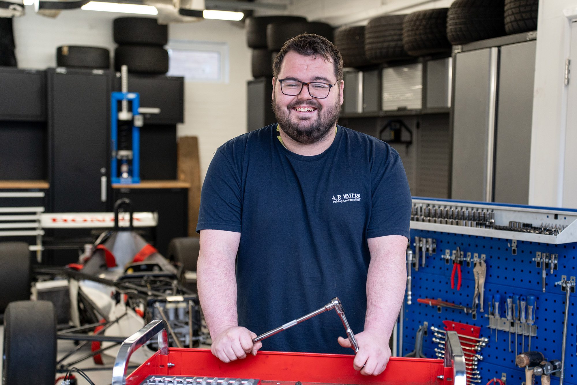 A learner looking at the camera with work-based tools.
