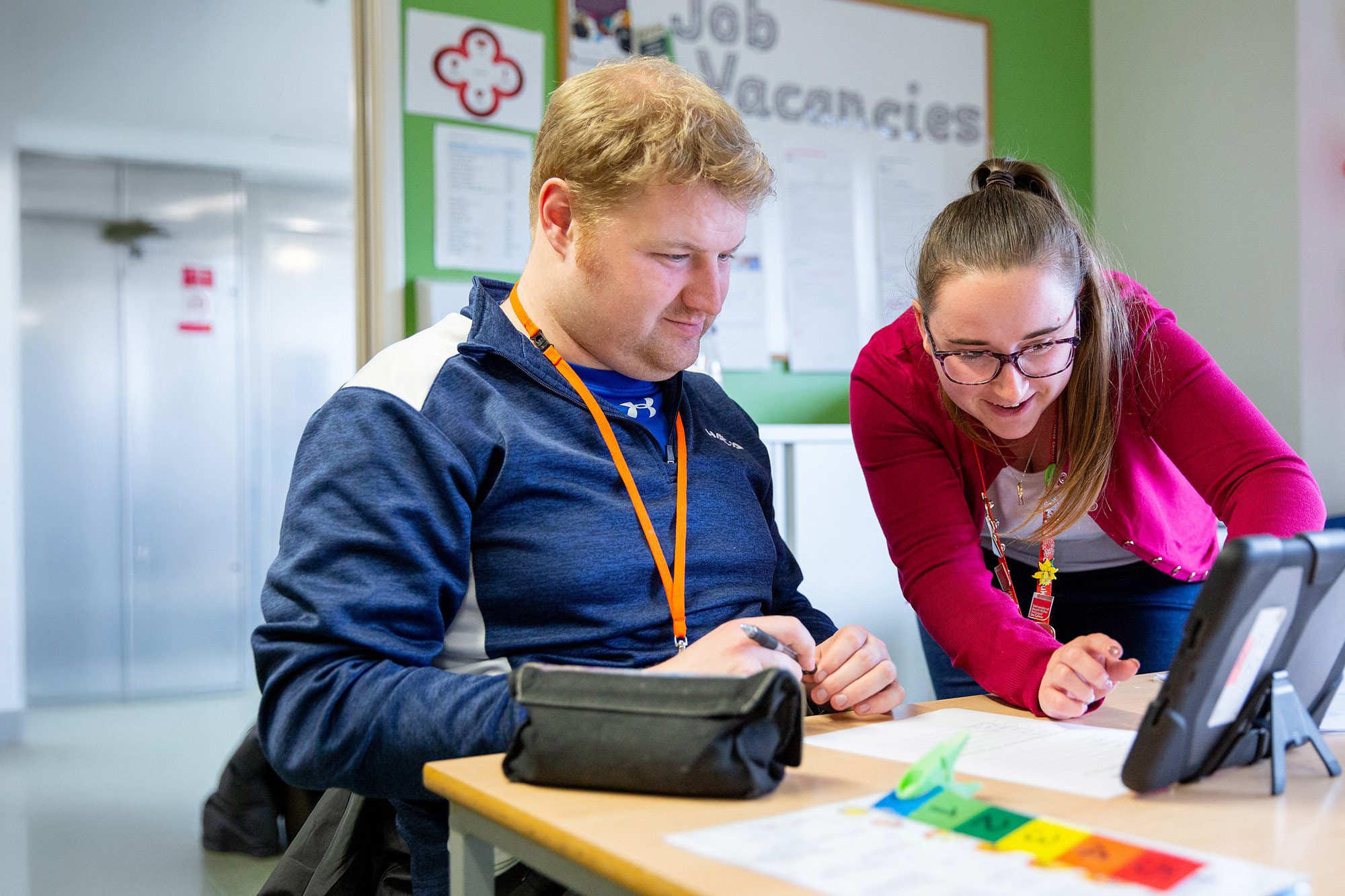 CG member of staff helping a learner with their work.